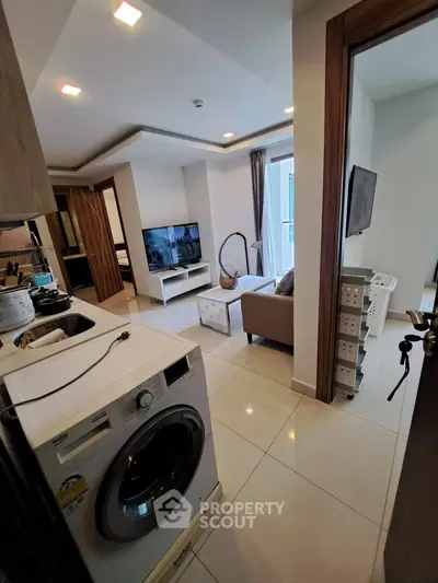 Modern apartment interior with open layout, featuring a cozy living area and in-unit washing machine.