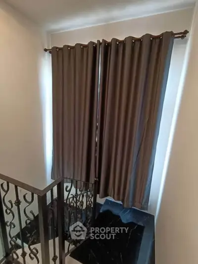 Elegant staircase with dark curtains and ornate railing in modern home