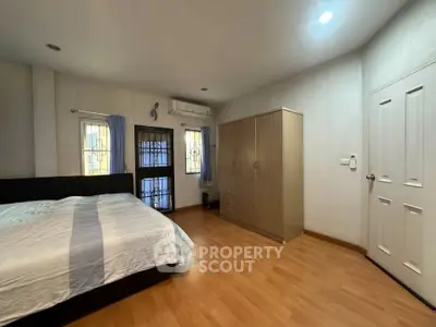 Spacious bedroom with wooden flooring and ample natural light