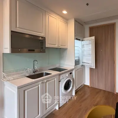 Modern kitchen with washing machine and sleek cabinetry in compact layout.