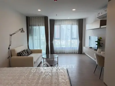 Modern studio apartment with large windows and stylish furnishings in a high-rise building.