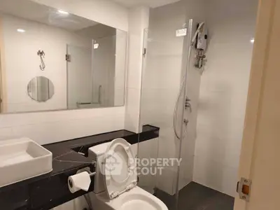 Modern bathroom with sleek design, featuring a glass shower enclosure and contemporary fixtures.