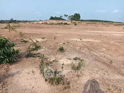 Expansive land plot with potential for development, featuring open terrain and distant greenery under a clear sky.