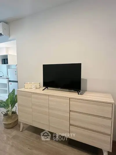 Modern living room with sleek wooden cabinet and flat-screen TV, showcasing minimalist interior design.