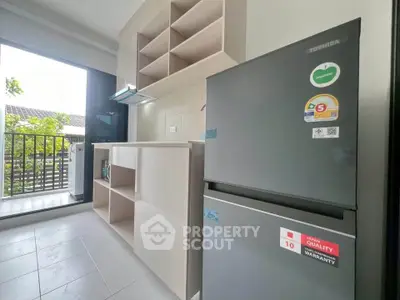 Modern kitchen with sleek appliances and open layout leading to a balcony with a view.