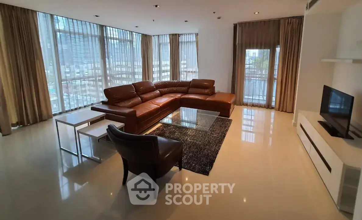 Spacious modern living room with large windows and stylish furniture in a high-rise apartment.