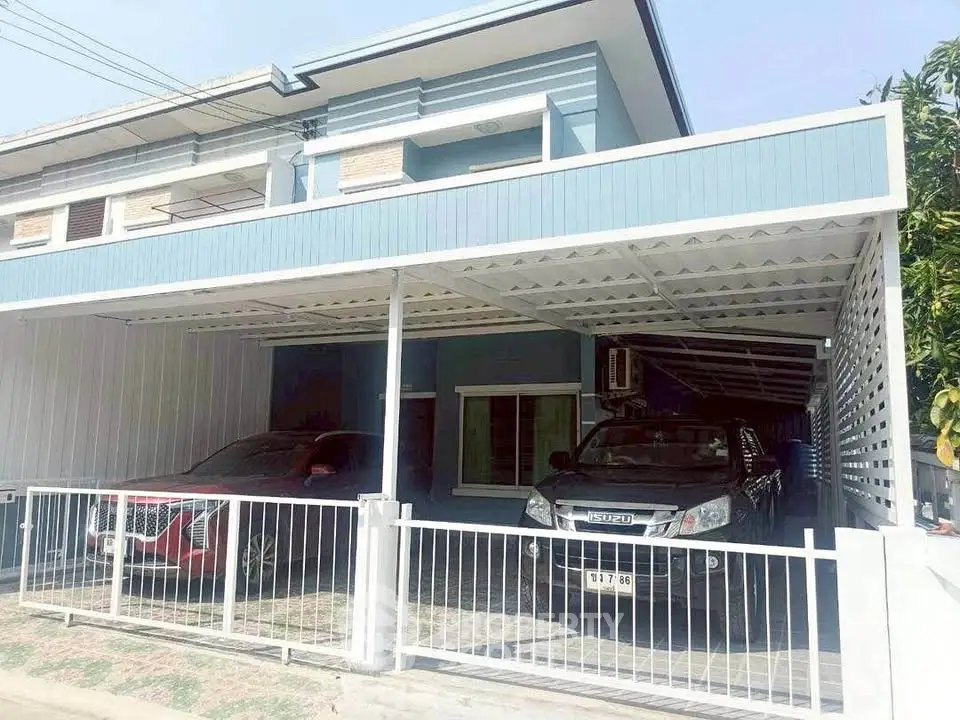 Modern residential property with covered parking for two vehicles, showcasing sleek design and secure fencing.