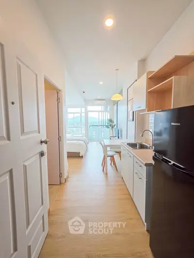 Modern studio apartment with open kitchen and scenic view, featuring sleek appliances and cozy dining area.