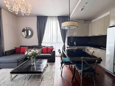 Stylish modern living room with elegant chandelier and open kitchen layout.