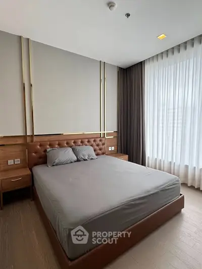 Luxurious bedroom with elegant decor and large window offering natural light.