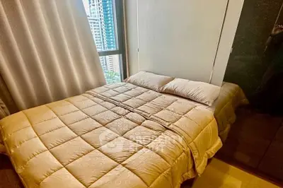 Cozy bedroom with city view, featuring a comfortable bed and modern decor.