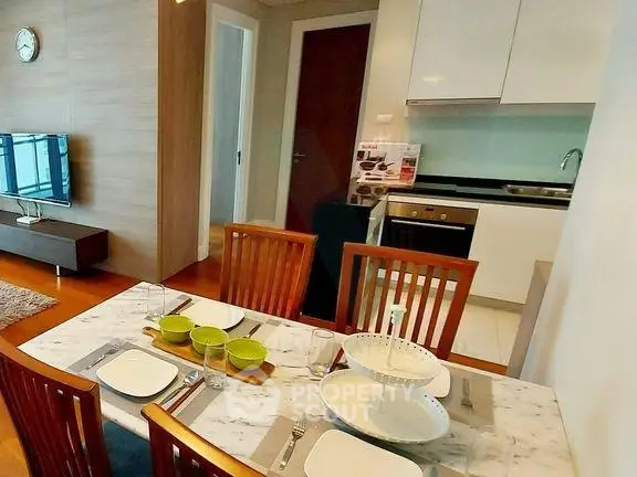 Modern dining and living area with sleek kitchen in open layout apartment.