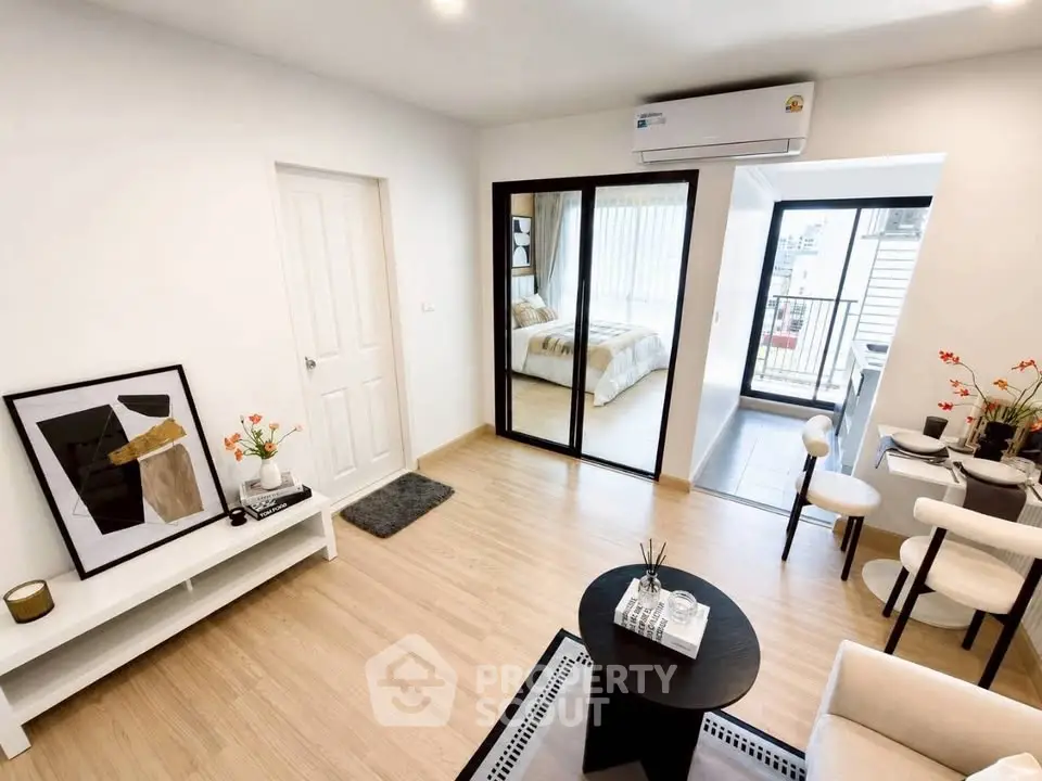 Modern open-plan living room with stylish decor and access to a cozy bedroom and balcony.