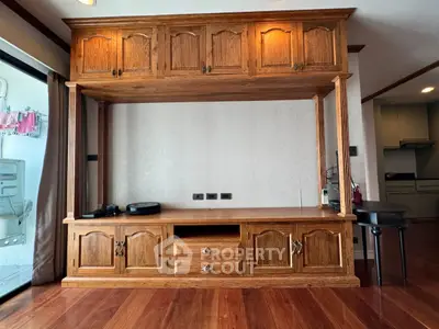Spacious living room with elegant wooden built-in entertainment center and hardwood floors.