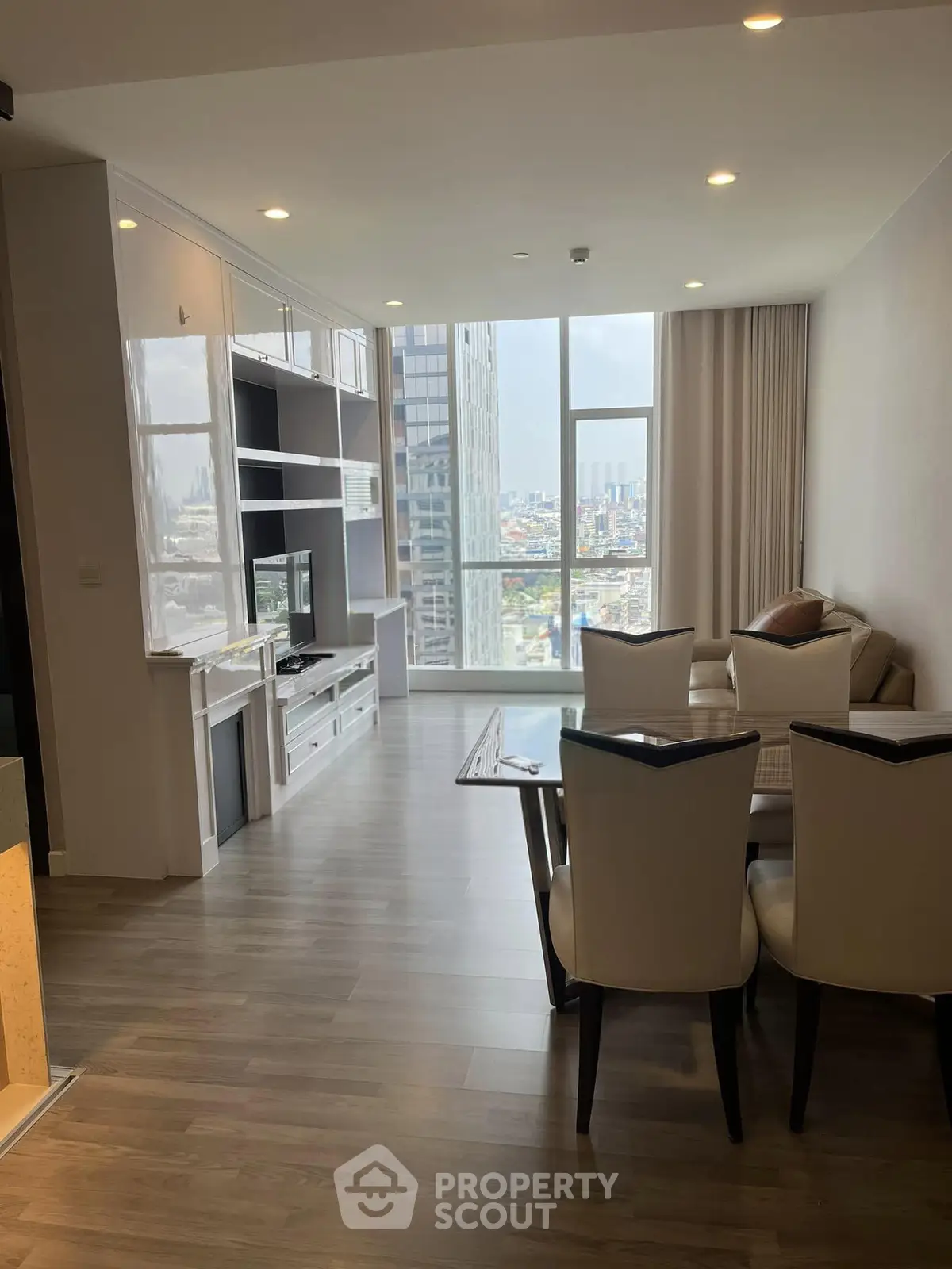 Spacious modern living room with city view, elegant dining area, and floor-to-ceiling windows.