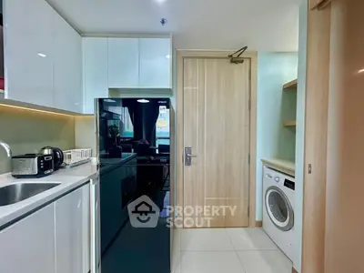 Modern kitchen with sleek appliances and washing machine in compact layout