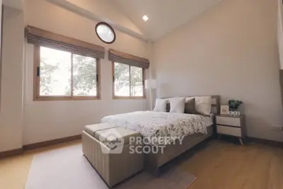 Spacious bedroom with modern decor and large windows offering natural light.