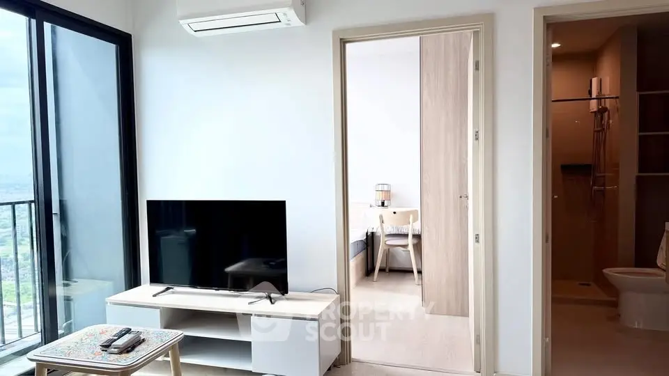 Modern living room with balcony view, TV setup, and adjacent dining area in a stylish apartment.