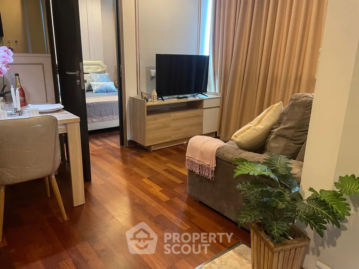 Cozy living room with wooden flooring, modern furniture, and a glimpse of a stylish bedroom.