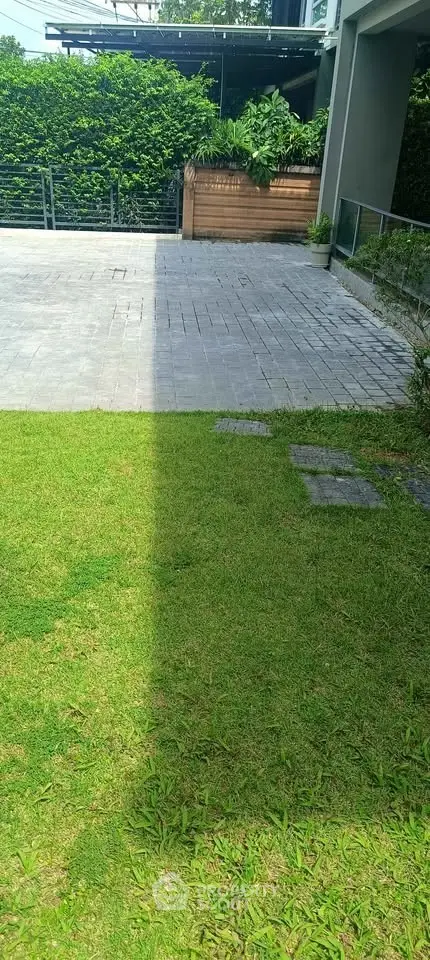 Spacious outdoor garden area with paved pathway and lush greenery, perfect for relaxation and outdoor activities.