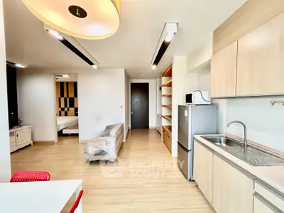 Modern open-layout apartment with sleek kitchen and spacious living area, featuring light wood finishes and contemporary design.