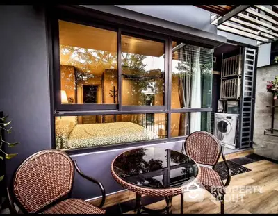 Modern apartment with cozy outdoor seating and large window view into bedroom