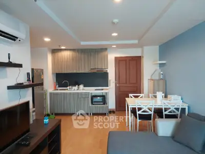 Modern open-layout living room with kitchen and dining area, featuring sleek cabinetry and contemporary furniture.