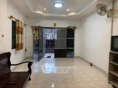 Spacious living room with open doors to a cozy patio, featuring tiled floors and ceiling fan.