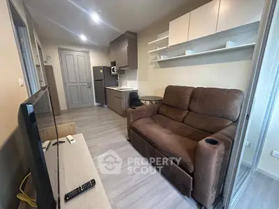 Modern living room with cozy brown sofa and sleek kitchen area in open layout apartment.