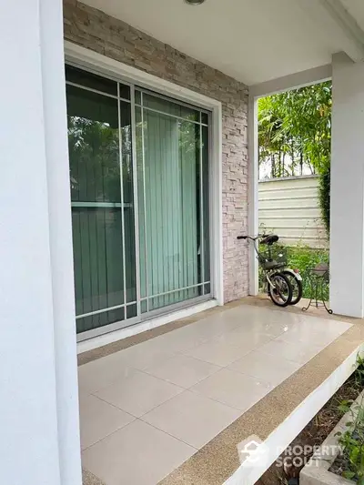 Charming entrance with tiled porch and greenery, perfect for a cozy home ambiance.