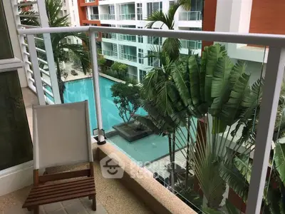 Luxurious balcony view overlooking a stunning pool and lush greenery in a modern apartment complex.