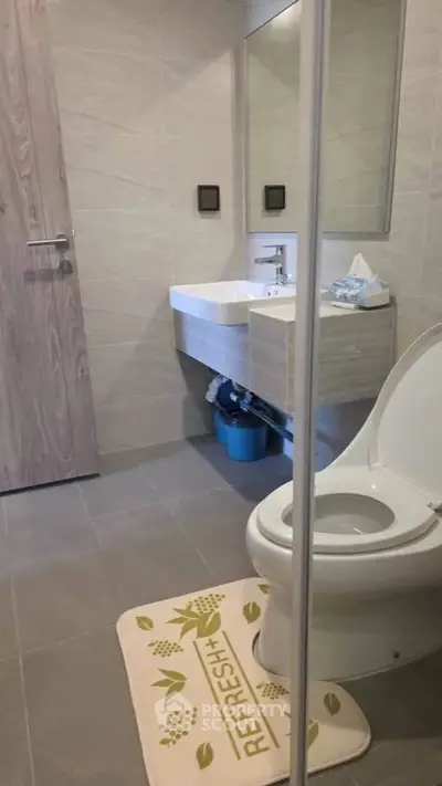 Modern bathroom with sleek fixtures and stylish design, featuring a contemporary sink and toilet.