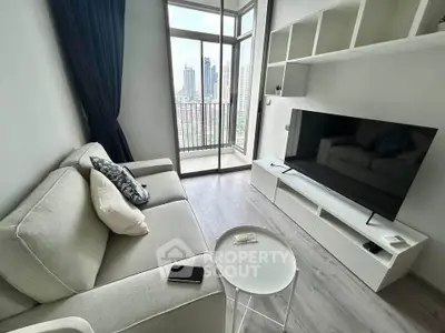 Modern living room with city view, featuring sleek furniture and large windows for natural light.