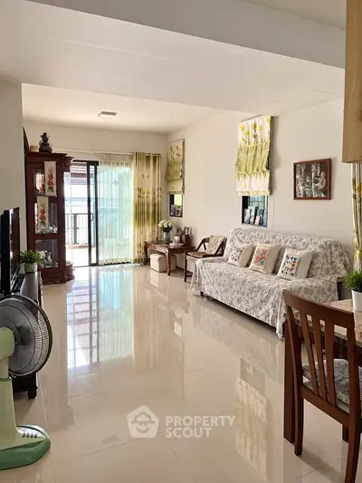 Spacious living room with elegant decor and large windows leading to a balcony.