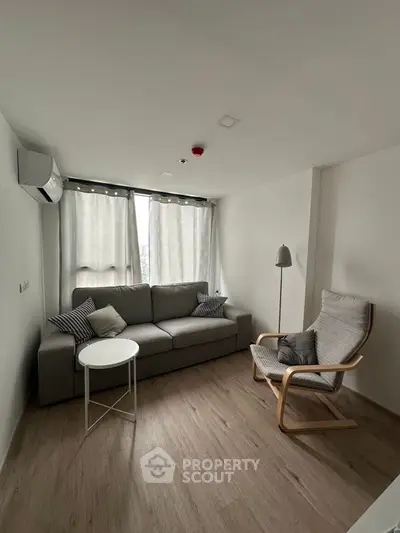 Modern living room with cozy sofa and armchair, minimalist design, bright natural light.