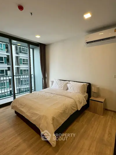 Modern bedroom with balcony view in a high-rise apartment, featuring wooden flooring and air conditioning.