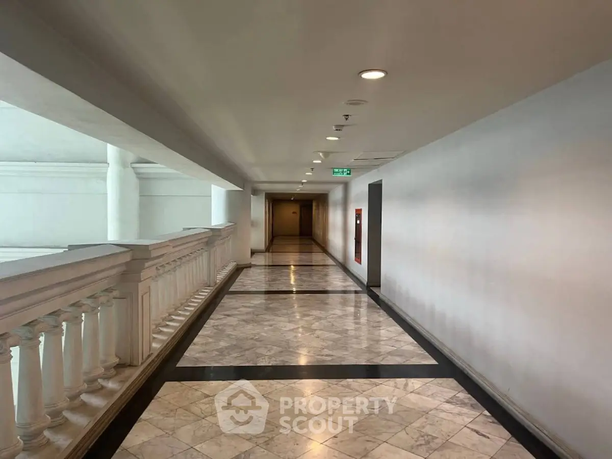 Elegant corridor with marble flooring and classic white balustrades in a luxury building.