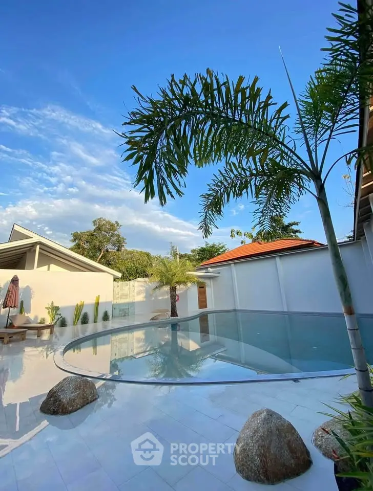 Stunning outdoor pool area with palm trees and clear blue sky, perfect for relaxation and leisure.