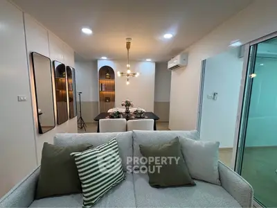 Modern living room with stylish decor and dining area, featuring cozy seating and elegant lighting.