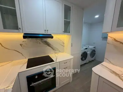 Modern kitchen with sleek appliances and adjacent laundry area
