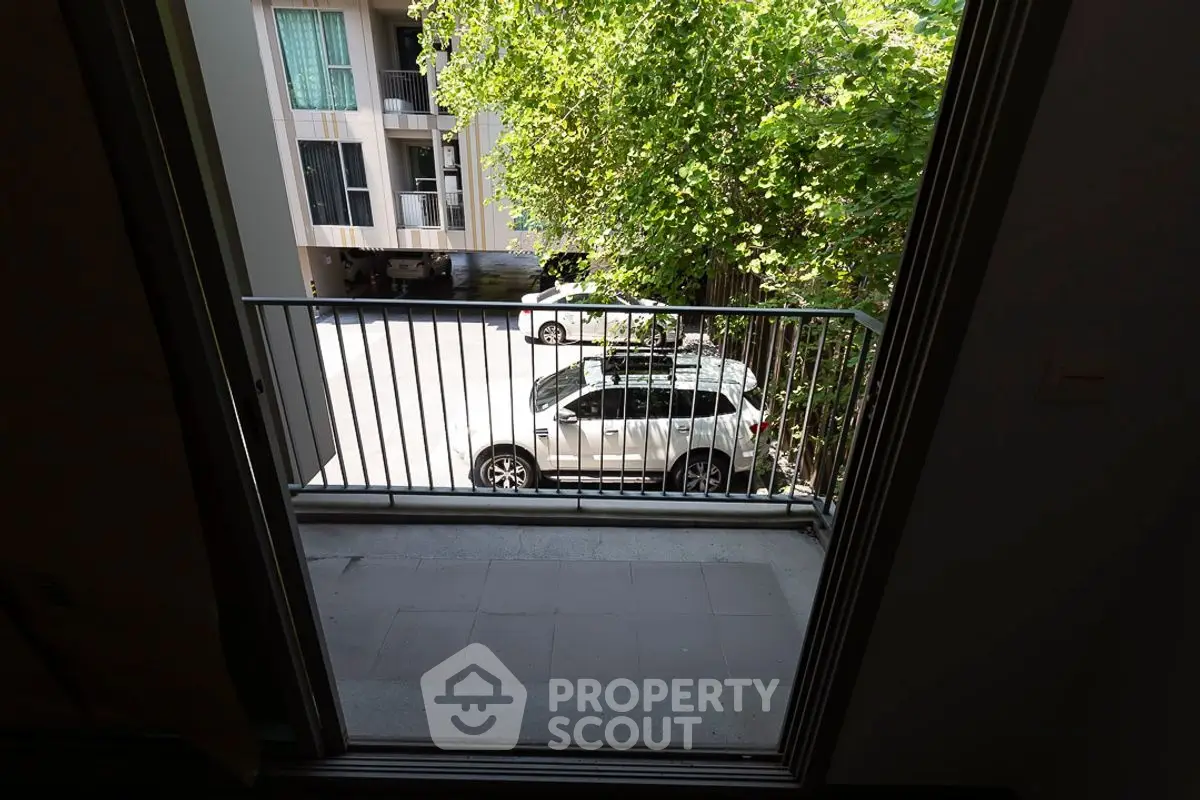 Charming balcony view overlooking a serene parking area with lush greenery.