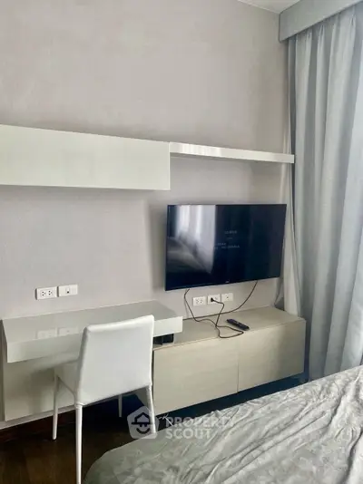 Modern bedroom with sleek desk, wall-mounted TV, and elegant curtains.
