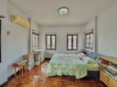 Spacious bedroom with parquet flooring and natural light