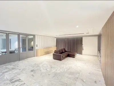 Spacious modern living room with marble flooring and sleek leather sofa.
