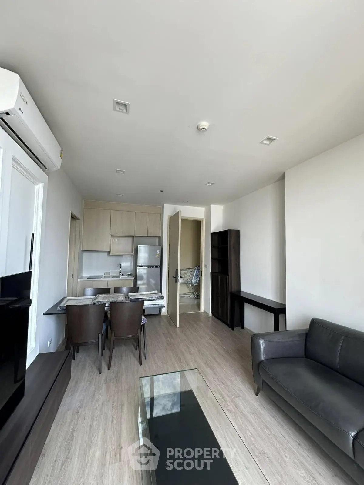 Modern living room with open kitchen, sleek furniture, and natural light