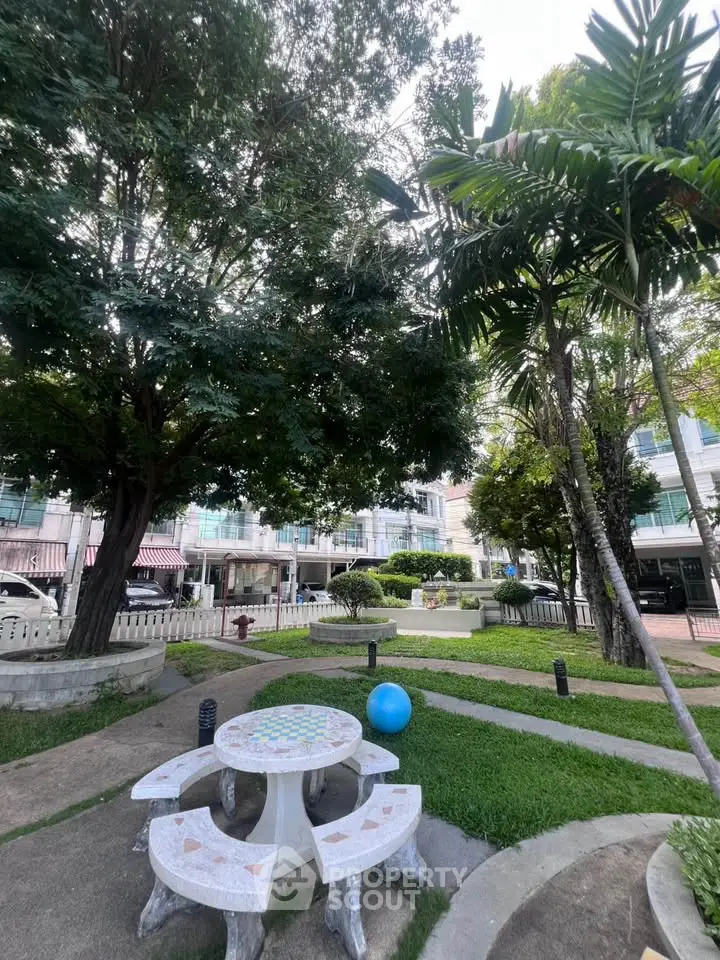 Charming garden area with seating and lush greenery in a residential complex.
