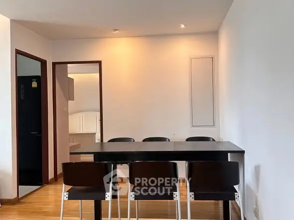 Modern dining area with sleek black table and chairs, adjacent to a cozy bedroom.