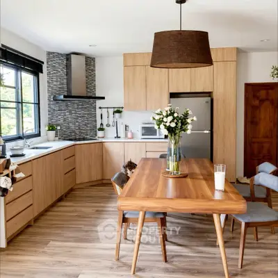 Modern kitchen with wooden cabinets, dining table, and stylish decor in a bright, open layout.