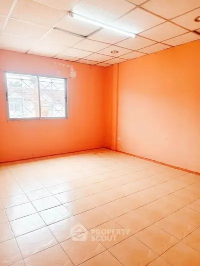 Spacious empty room with peach walls and tiled floor, ideal for customization.
