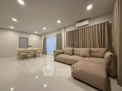 Spacious modern living room with elegant beige sofa and dining area, perfect for family gatherings.